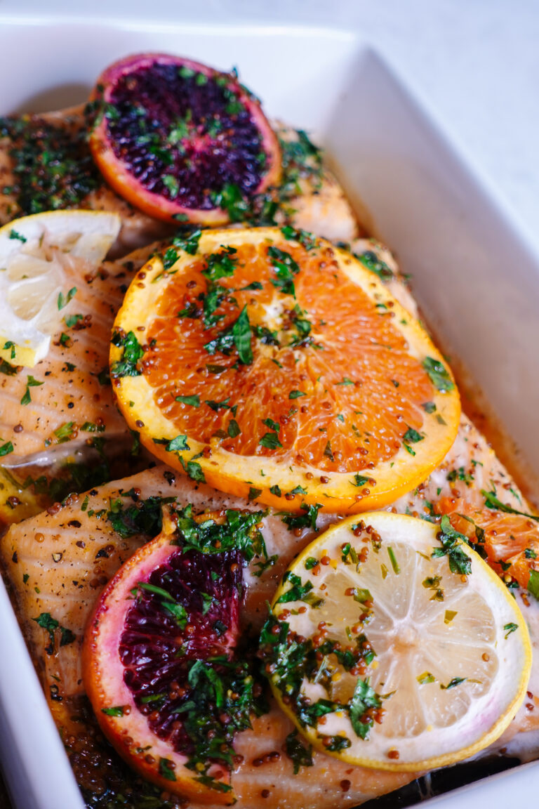 honey citrus salmon with lemon and orange slices on top served with broccolini