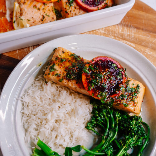 honey citrus salmon with lemon and orange slices on top served with broccolini