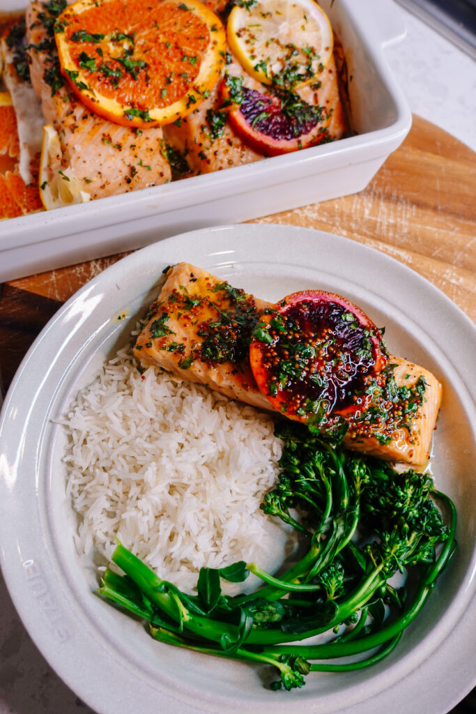 honey citrus salmon with lemon and orange slices on top served with broccolini